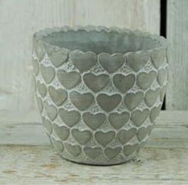 A chic flower pot made from stone with a whitewash finish and heart pattern.